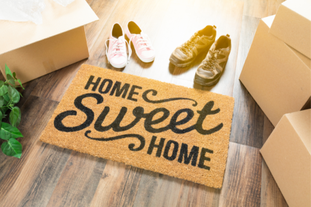 Doormat saying Home sweet home and 2 pairs of shoes on wooden floor