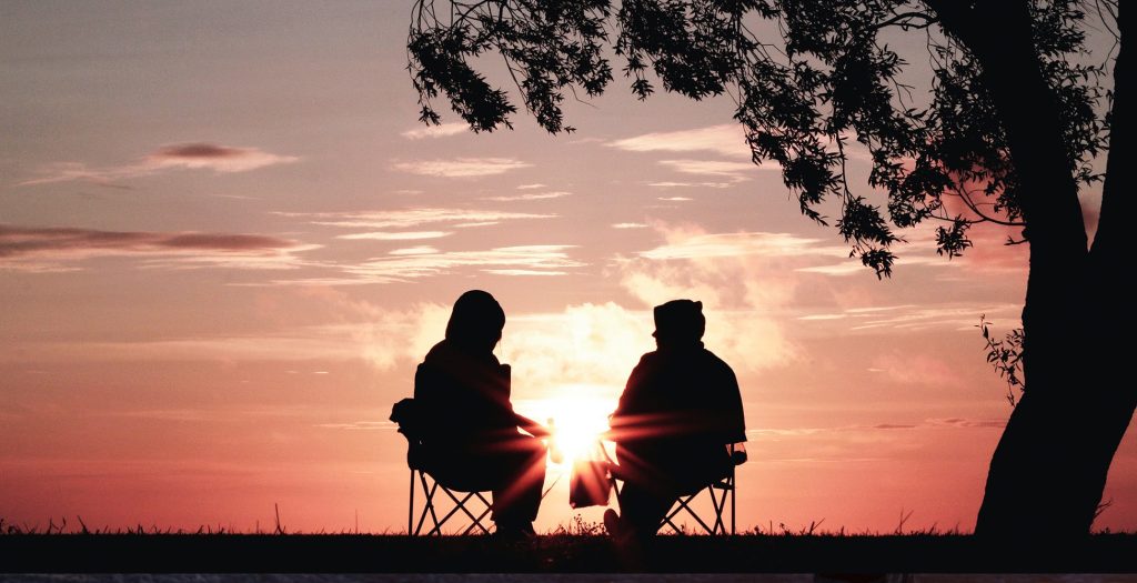 couple sitting under tree watching sunset