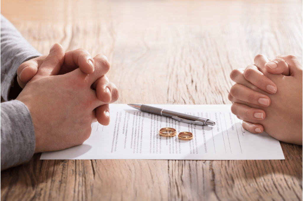 two pairs of clasped hands facing each other on table with document
