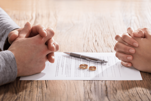 two pairs of clasped hands facing each other on table with document