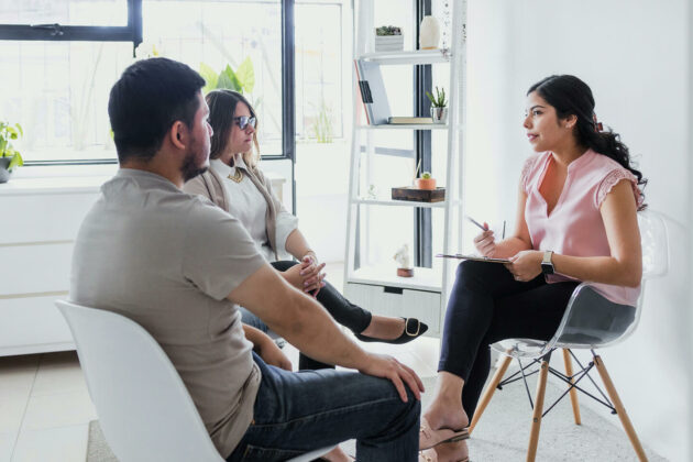 A couple attending a formal meeting with a solicitor sat in a white office mid-conversation.