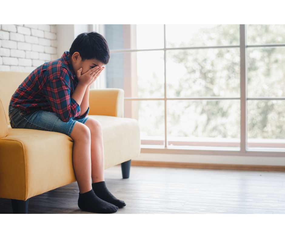 child sitting on sofa with hands covering face