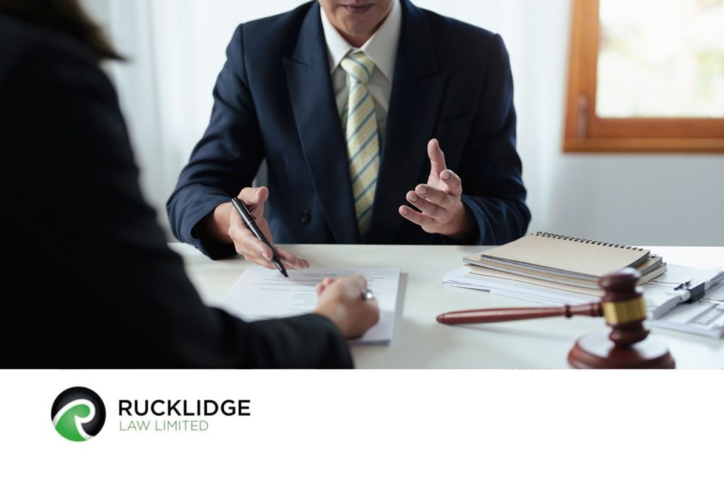 man in suit sitting at desk with back view of person in foreground looking at a document
