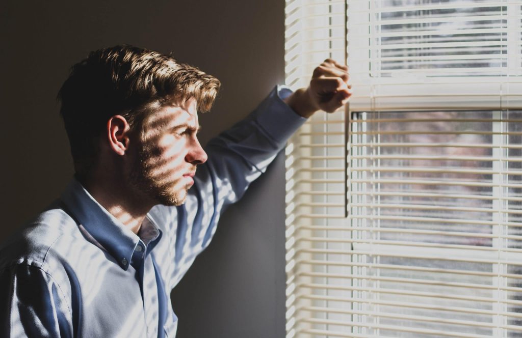 man standing in front of window looking pensive