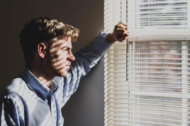 man standing in front of window looking pensive