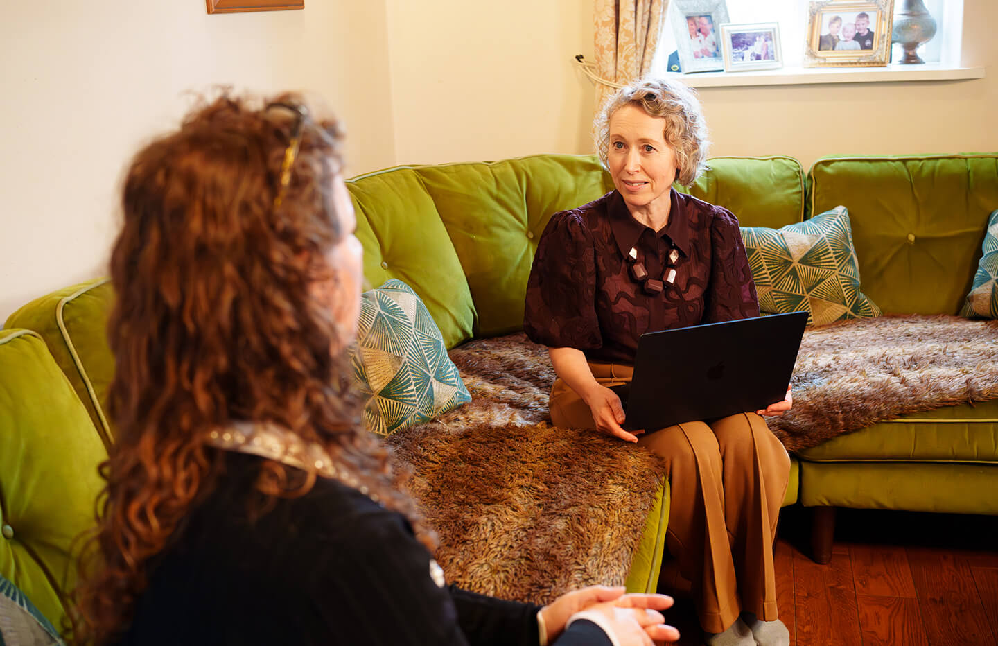 Solicitor sat in meeting in rustic house setting sat speaking to cleint on sofa.