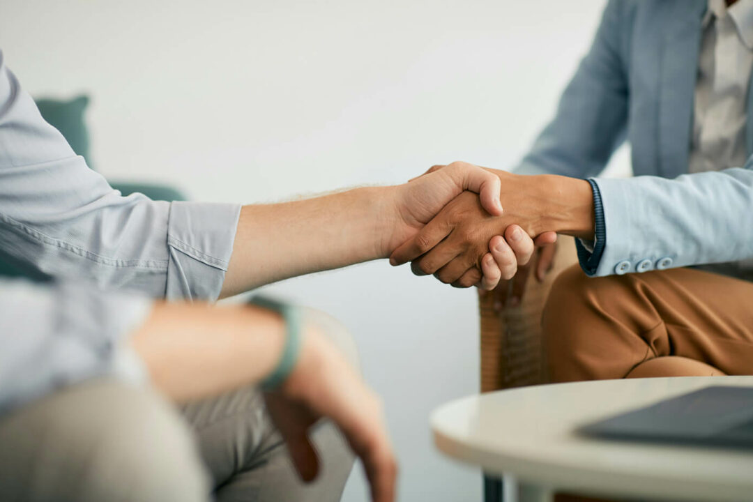 Close up of a hand shake in a modern clean meeting room.
